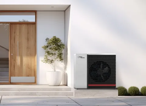 Alpha Innotec Wärmepumpe neben Hauseingang vor modernem Haus.