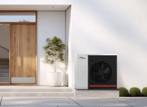 Alpha Innotec Wärmepumpe neben Hauseingang vor modernem Haus.