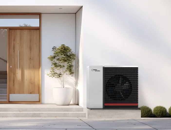 Alpha Innotec Wärmepumpe neben Hauseingang vor modernem Haus.