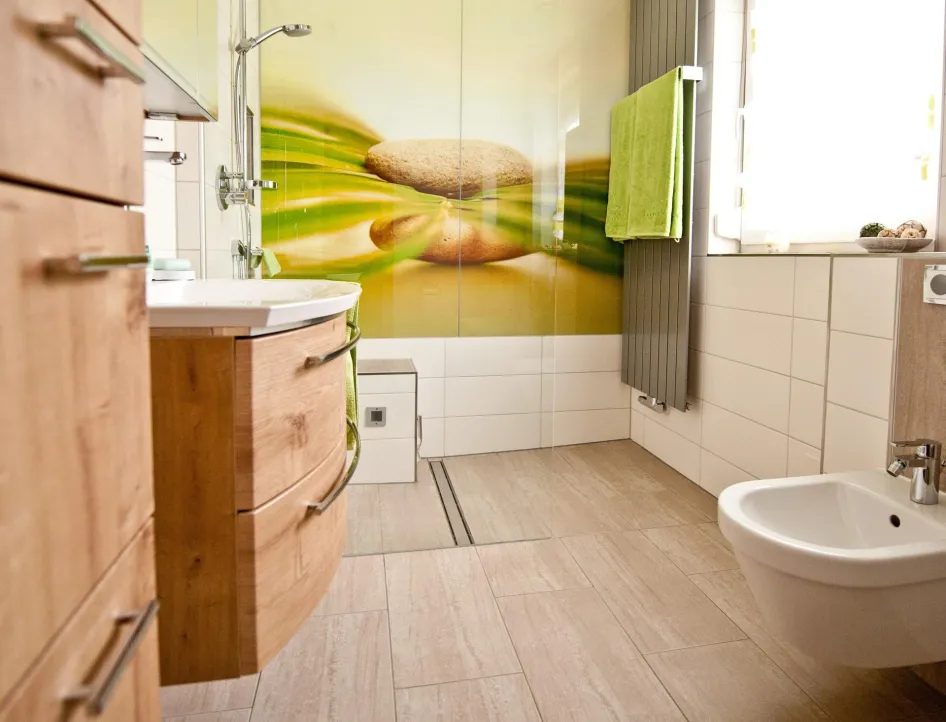 Modernes Badezimmer mit Holz-Möbeln, ebenerdiger Dusche mit Glaswand und Naturmotiv, wandhängendem Bidet und großen beige-farbenen Fliesen.